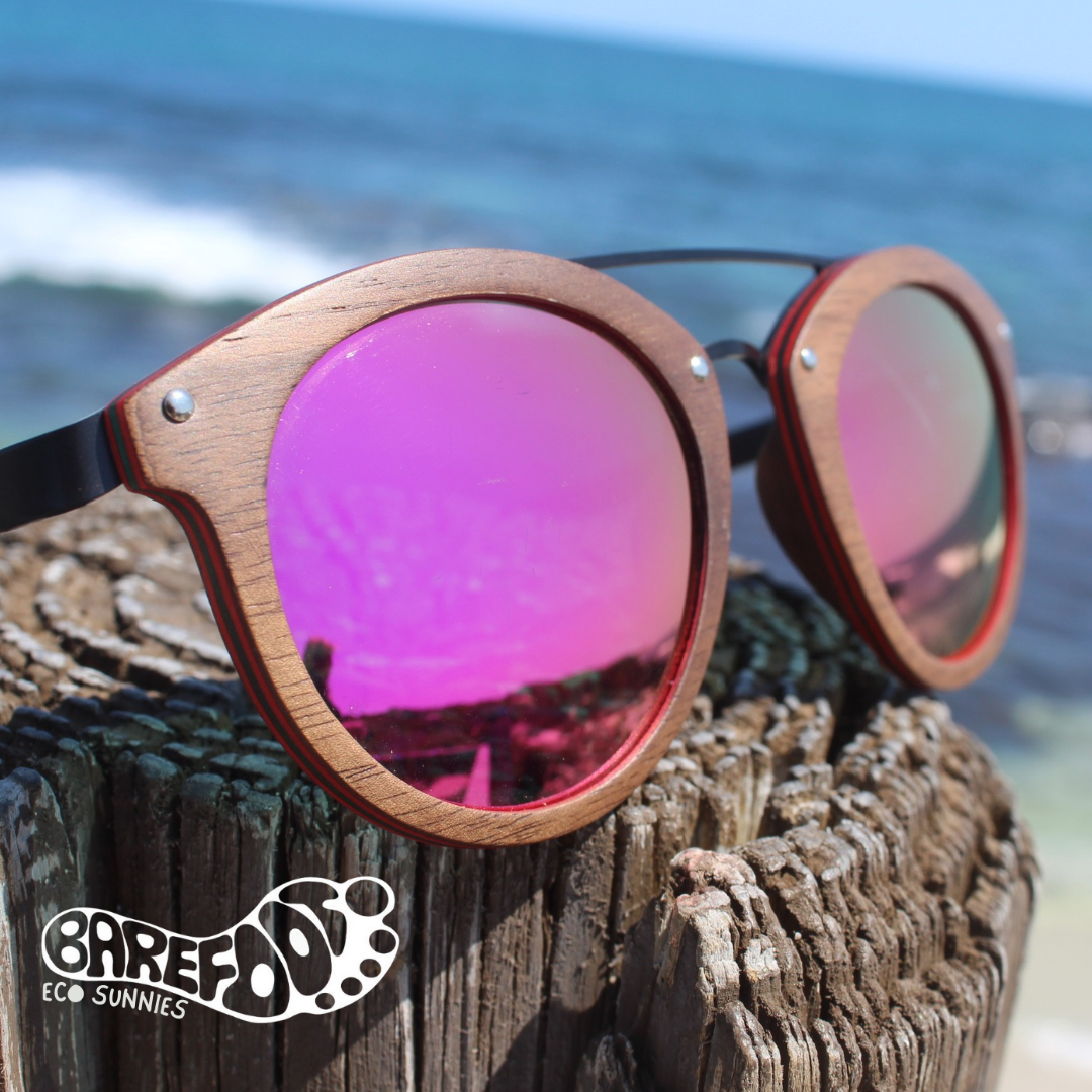 Barefoot Eco Daydream Island pink lens sunglasses on coastal timber